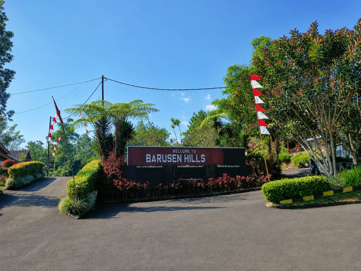 The entrance gate to Barusen Hills, framed by trees under a clear sky